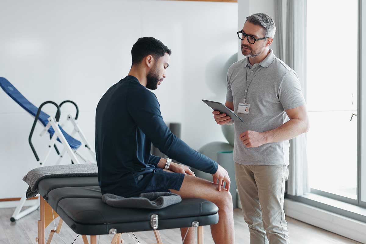 man-dealing-with-knee-pain-talking-to-a-person-regarding-rehab